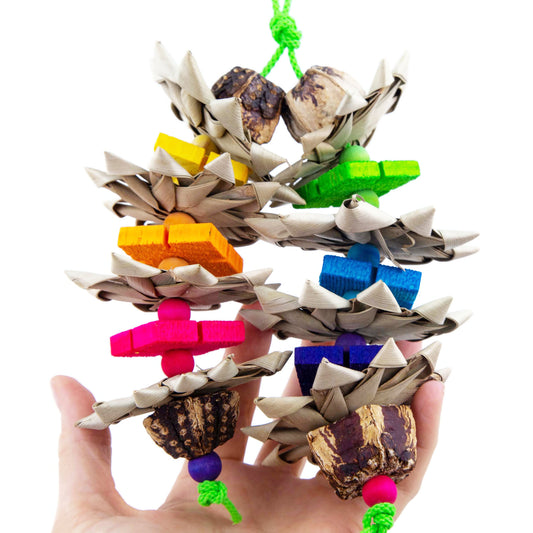 Bird toy with colorful wooden blocks and natural materials held in a hand against a white background