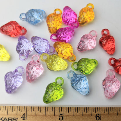 Assorted colorful strawberry-shaped charms with a ruler for scale on a white background