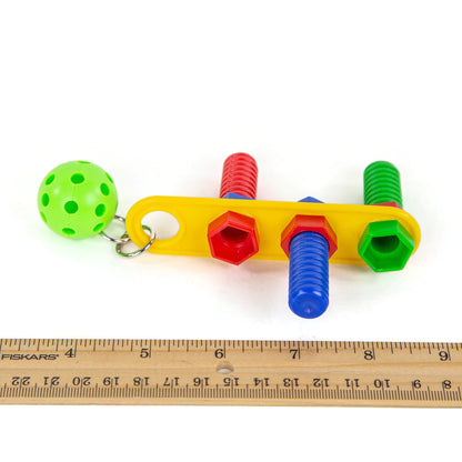 Colorful toy with screws and a ball on a white background, measured by a ruler. It is about 6 and a half inches long by 3 and a half inches wide.