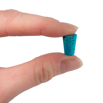 Hand holding a small blue cork against a white background