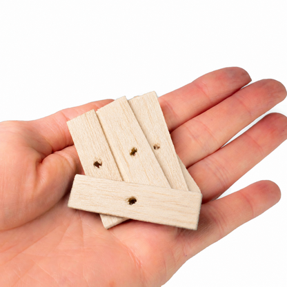 Hand holding four small wooden blocks with holes on a white background