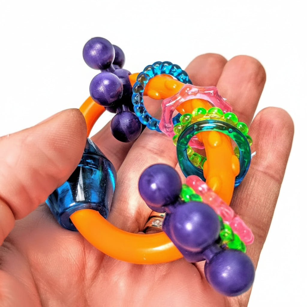 Colorful parrot foot toy held in a hand against a white background