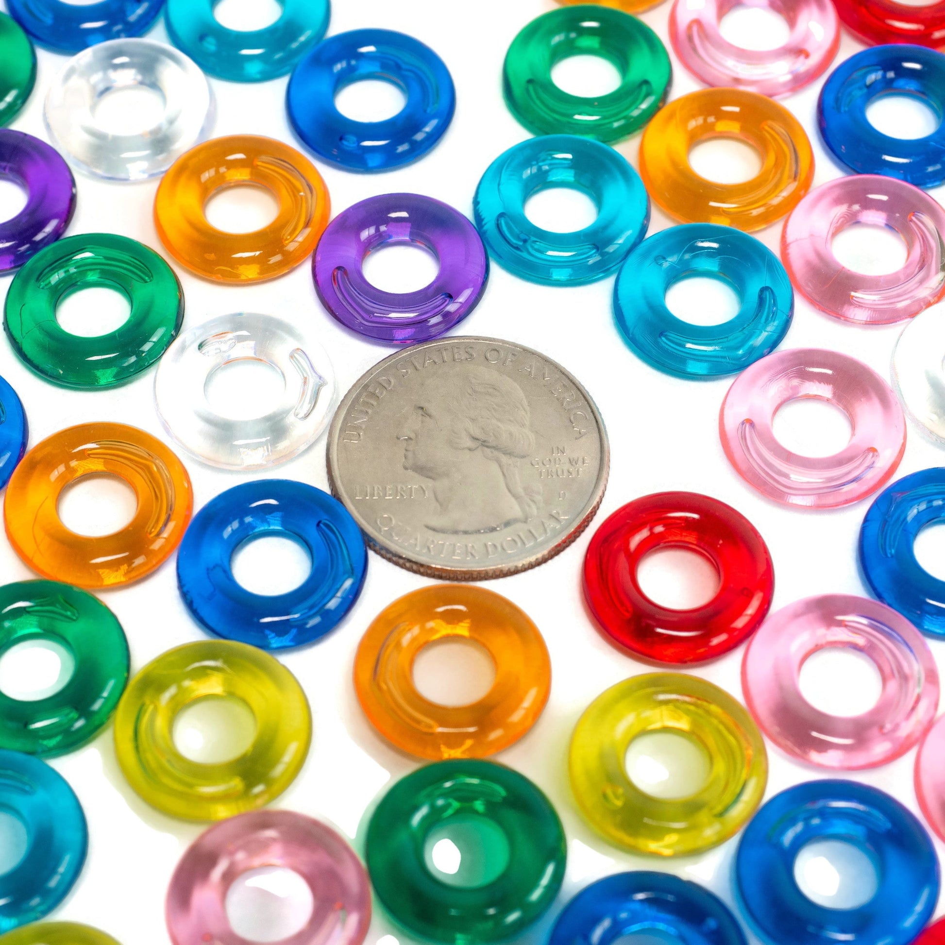 Colorful plastic rings with a quarter for size comparison on a white background